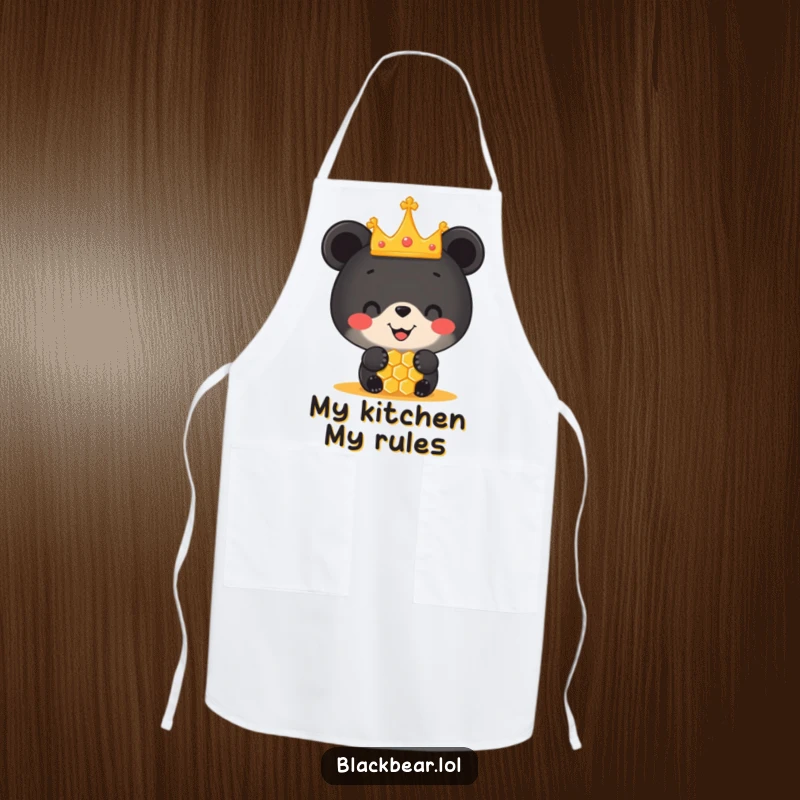 Funny apron showing a black bear cub in a tiny crown balancing a honeycomb on its nose, ready for kitchen duty with a smile.