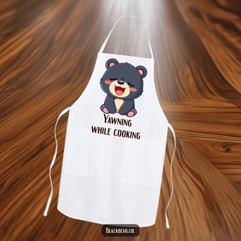 Funny apron featuring a sleepy black bear cub yawning with a big smile, perfect for relaxed cooking.