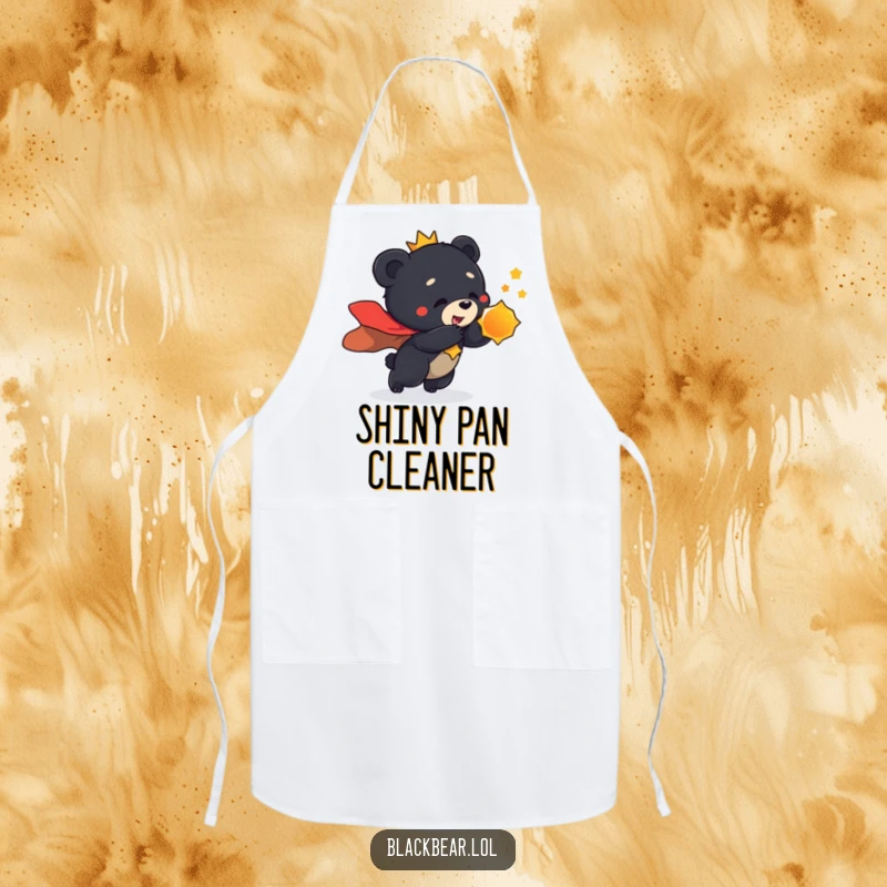 Funny apron showing a black bear cub in a regal cape, playfully lunging towards a shiny object, ready for culinary conquest.