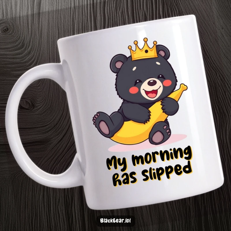 Funny black bear cub wearing a crown hilariously slips on a banana peel with a big giggle on this mug.