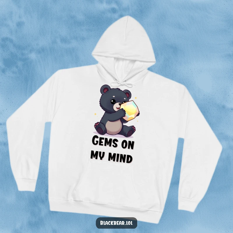Funny hoodie depicting a black bear cub reaching for a large, dazzling gem, perfect for cozy adventures.