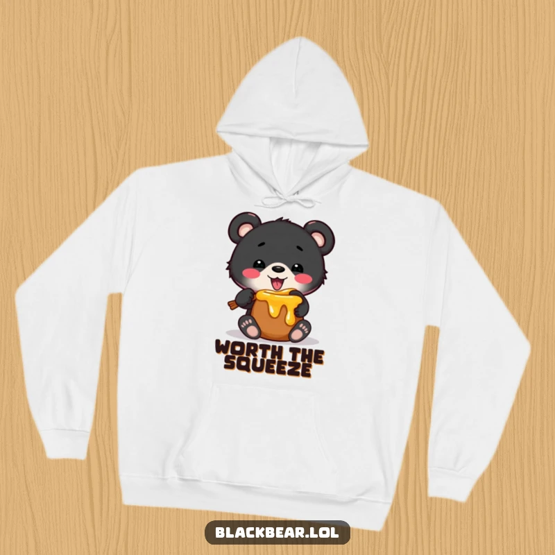 Funny hoodie showing a black bear cub hilariously stuck in a small honey pot, perfect for cozying up with a sweet sense of humor.