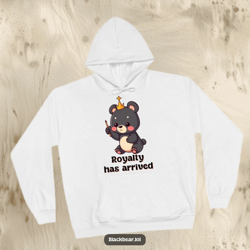 Funny black bear cub with a miniature scepter pointing skyward, featured on a warm hoodie, a perfect funny gift for all.