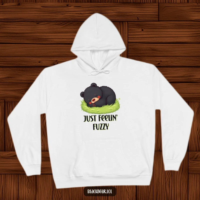 Funny hoodie featuring a black bear cub joyfully rolling in a soft mossy bed, offering warmth and a hug of nature's comfort.