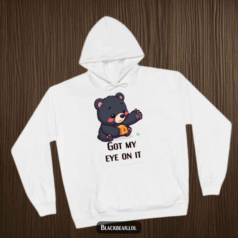 Funny hoodie featuring a sweet black bear cub showcasing incredible balance by holding a small, shiny treasure on its nose with a proud expression.
