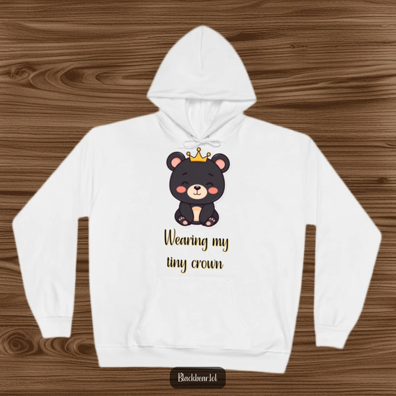 Funny black bear character with a gentle smile and a small crown, depicted on a cozy hoodie, offering warmth and dignity.
