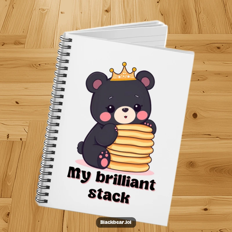 Funny crowned black bear cub balancing a stack of pancakes, featured on the cover of this humorous notebook.
