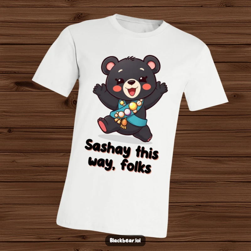 Funny t-shirt depicting a black bear cub wearing a sparkly sash, caught mid-silly dance with an ecstatic expression.