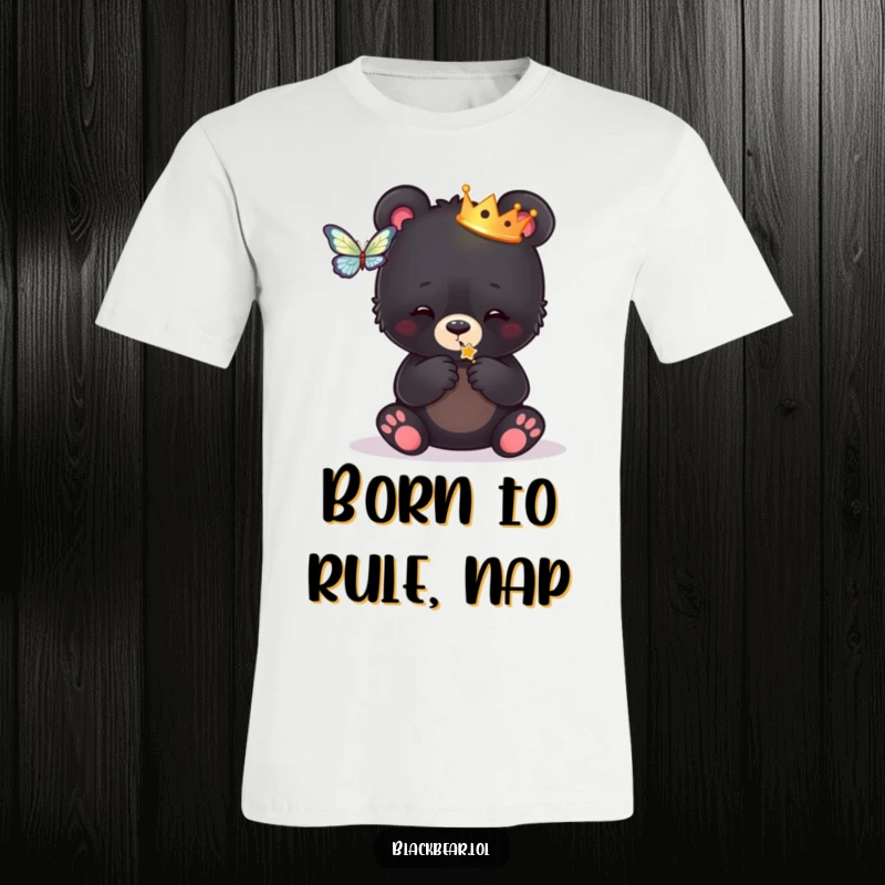 Funny t-shirt showcasing a black bear cub in a small crown, joyfully swiping at a butterfly, embodying playful royal charm.