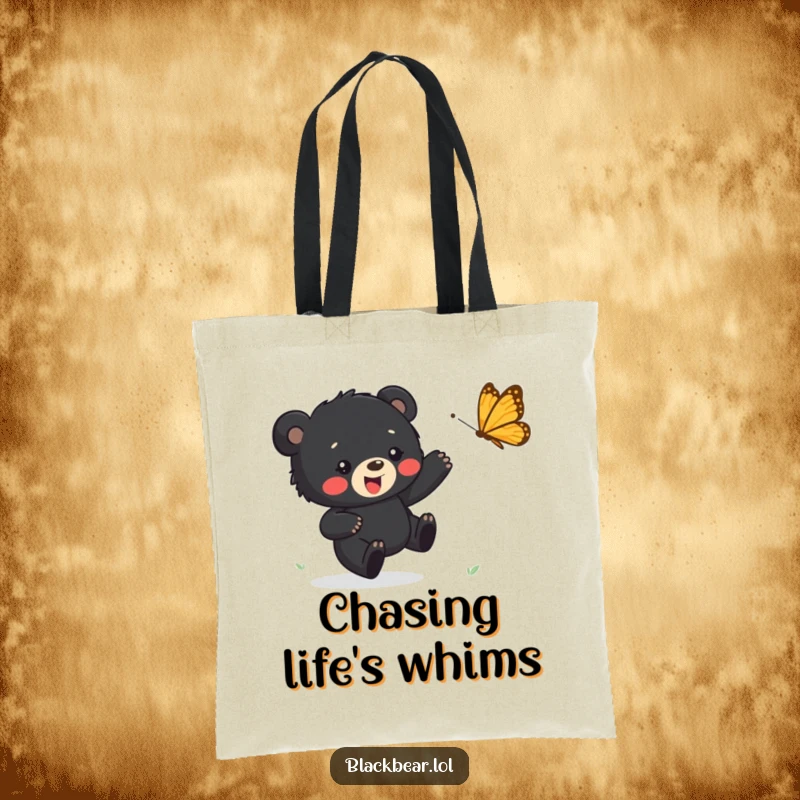Funny tote bag depicting a happy black bear cub in pursuit of a fluttering butterfly, ideal for carrying items with a smile.