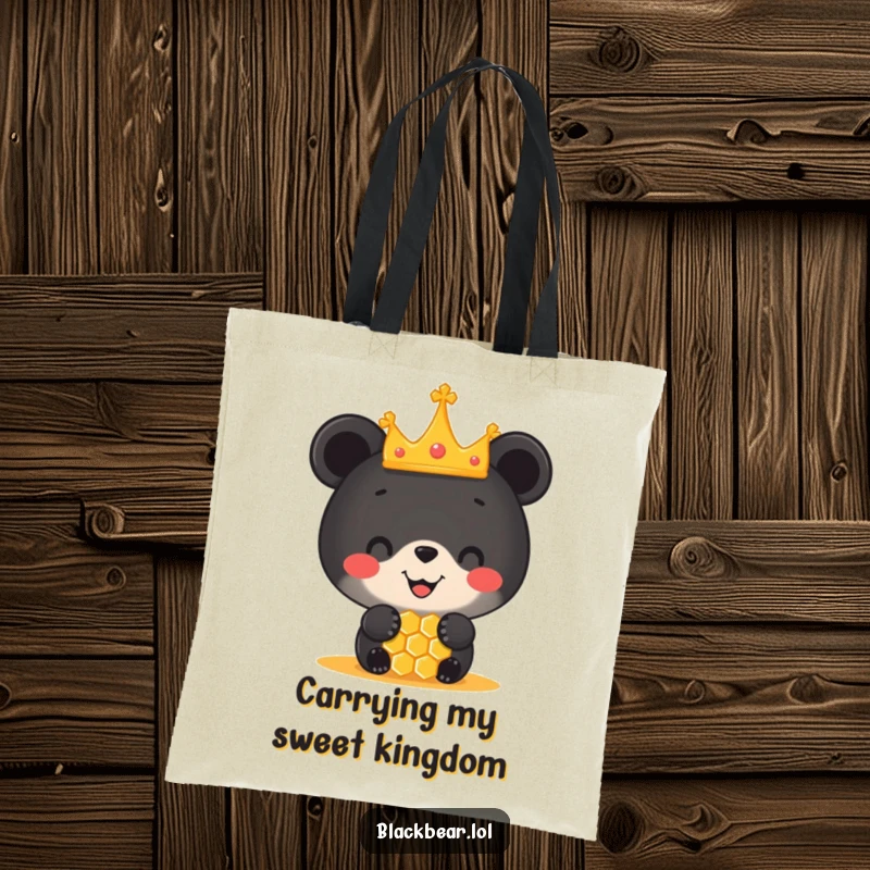 Funny tote bag featuring a black bear cub in a miniature crown balancing a honeycomb on its nose, perfect for carrying joy.