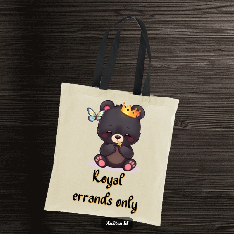 Funny tote bag with a black bear cub wearing a crown, playfully engaged with a butterfly, showcasing whimsical royal vibes.